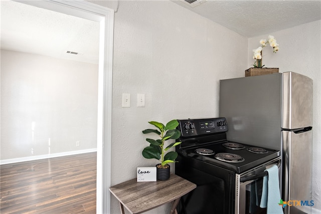 kitchen featuring a textured ceiling, black range with electric cooktop, dark hardwood / wood-style floors, and stainless steel refrigerator