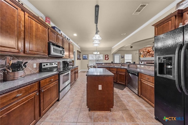 8717 Surrey Ct, Temple, TX 76502 - kitchen with appliances with stainless steel finishes, dark countertops, a peninsula, decorative backsplash, and a kitchen island