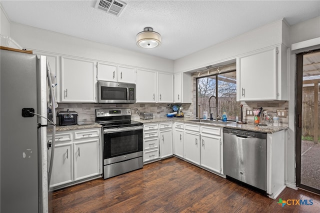 kitchen featuring sink, light stone counters, appliances with stainless steel finishes, dark hardwood / wood-style floors, and white cabinets