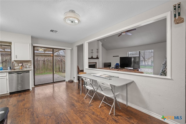 kitchen with white cabinetry, dark hardwood / wood-style flooring, stainless steel dishwasher, ceiling fan, and a textured ceiling