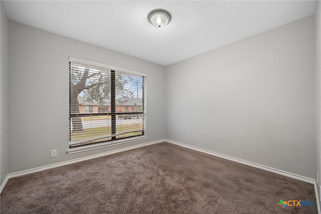 spare room with dark carpet and a textured ceiling