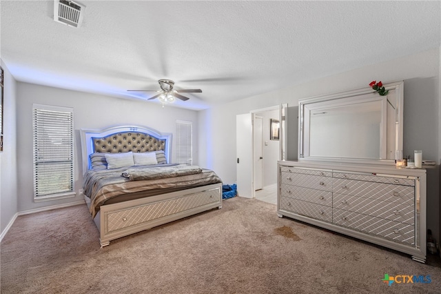 bedroom with ceiling fan, light carpet, and a textured ceiling