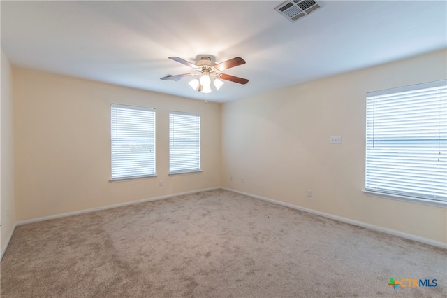 empty room featuring ceiling fan, light carpet, and a healthy amount of sunlight