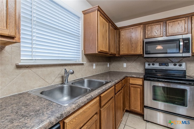 kitchen featuring stainless steel appliances, sink, tasteful backsplash, and light tile patterned floors