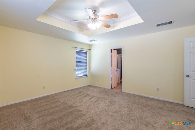 carpeted spare room with ceiling fan, crown molding, and a tray ceiling