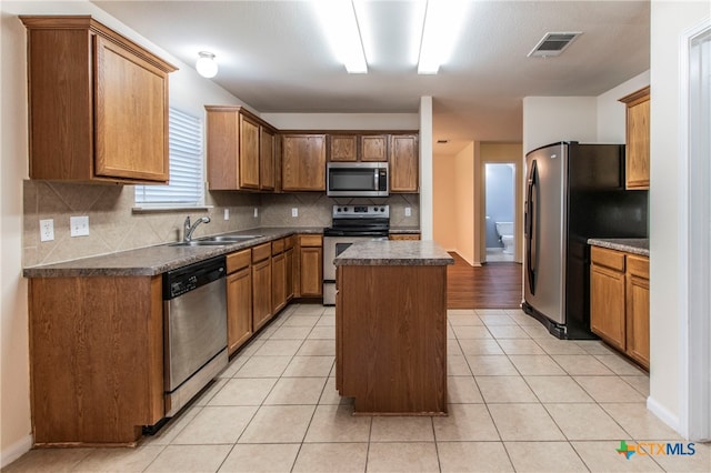 kitchen featuring decorative backsplash, appliances with stainless steel finishes, sink, and a center island