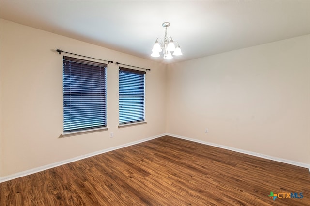 spare room with dark hardwood / wood-style flooring and a notable chandelier