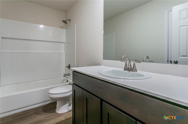 full bathroom with wood-type flooring, toilet,  shower combination, and vanity