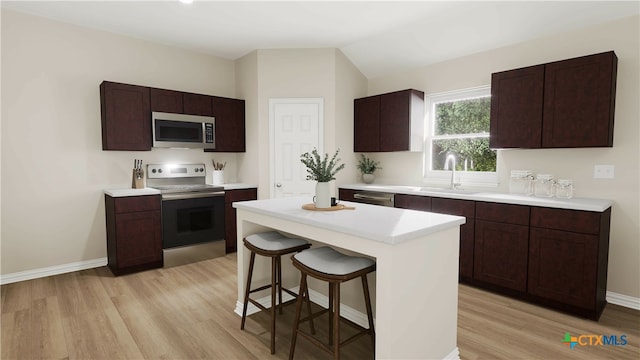 kitchen with a breakfast bar area, sink, a kitchen island, light wood-type flooring, and appliances with stainless steel finishes