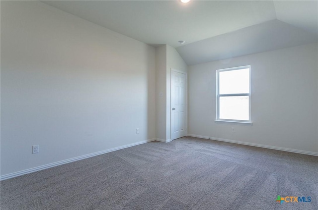 empty room featuring vaulted ceiling and carpet