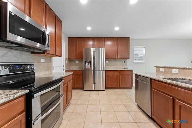 3907 Gentle Mdw, New Braunfels, TX 78130 - kitchen with appliances with stainless steel finishes, a sink, tasteful backsplash, brown cabinets, and light tile patterned floors