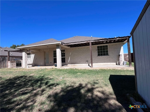 back of property featuring area for grilling, a patio area, and a yard