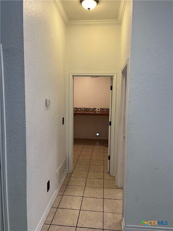 hall with crown molding and light tile patterned flooring