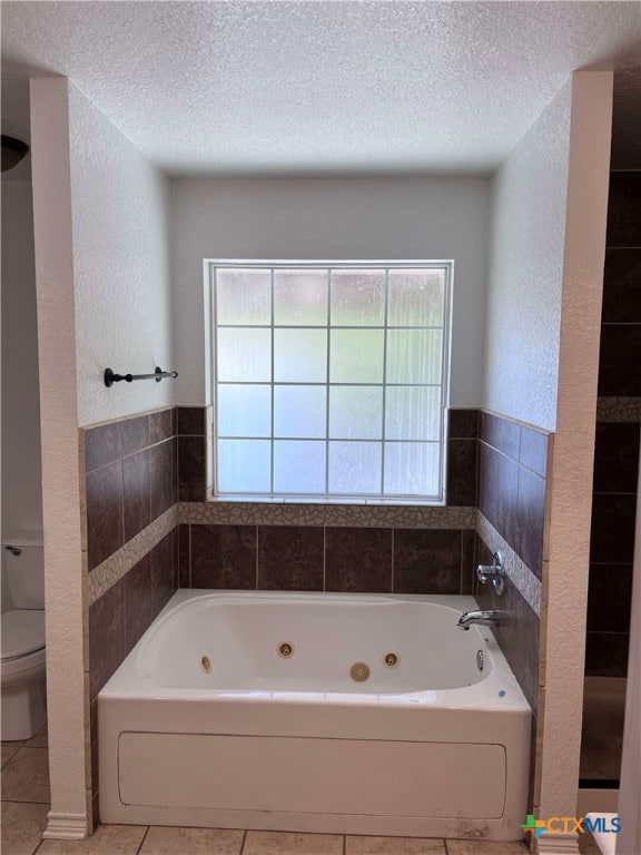 bathroom with tile patterned flooring, a textured ceiling, toilet, and a bathing tub