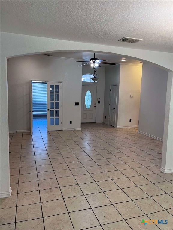 foyer featuring light tile patterned floors, a textured ceiling, and ceiling fan