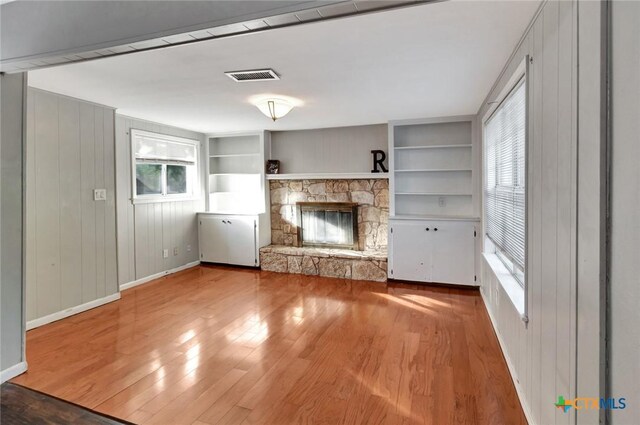 1808 Mission Dr, Victoria, TX 77901 - unfurnished living room with baseboards, a stone fireplace, wood finished floors, and built in shelves