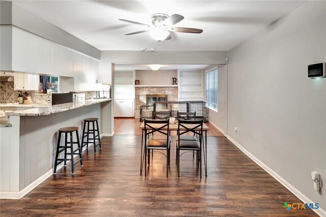 1808 Mission Dr, Victoria, TX 77901 - dining space with a ceiling fan, dark wood finished floors, a fireplace, and baseboards