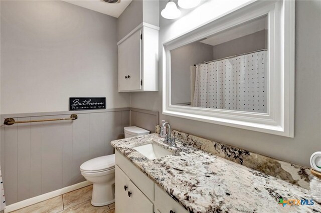 1808 Mission Dr, Victoria, TX 77901 - full bath with vanity, toilet, wainscoting, tile patterned floors, and curtained shower