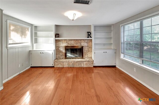 1808 Mission Dr, Victoria, TX 77901 - unfurnished living room with built in shelves, wood finished floors, a stone fireplace, and baseboards