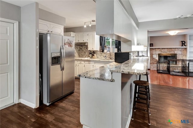 1808 Mission Dr, Victoria, TX 77901 - kitchen with stainless steel refrigerator with ice dispenser, a peninsula, dark wood finished floors, light stone countertops, and white cabinetry