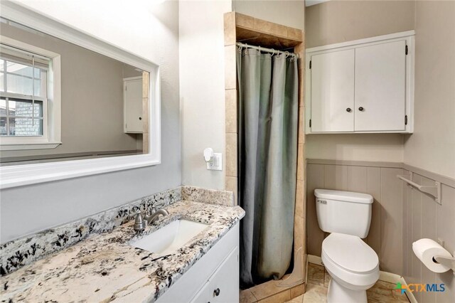 1808 Mission Dr, Victoria, TX 77901 - full bathroom with vanity, toilet, curtained shower, and wainscoting