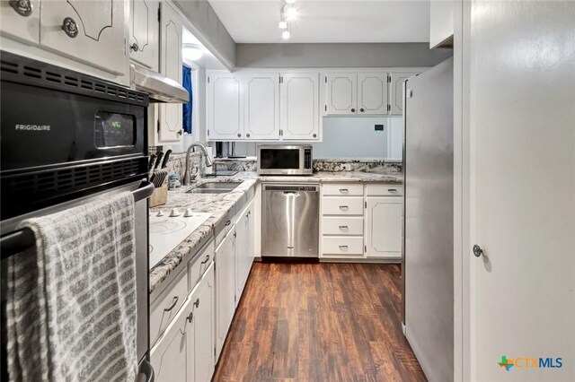 1808 Mission Dr, Victoria, TX 77901 - kitchen with stainless steel appliances, a sink, white cabinets, dark wood finished floors, and light stone counters