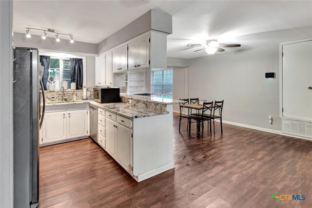1808 Mission Dr, Victoria, TX 77901 - kitchen with stainless steel appliances, a peninsula, ceiling fan, dark wood-style flooring, and light stone countertops