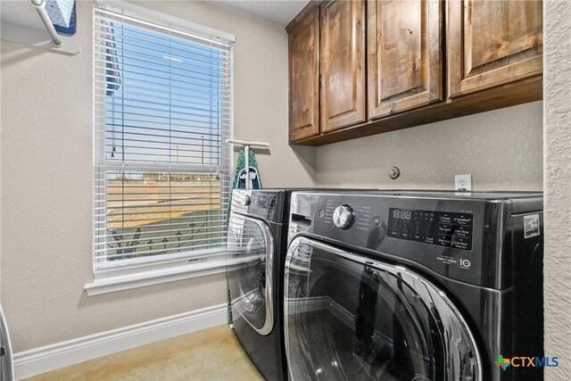 laundry room with cabinets, plenty of natural light, and washing machine and dryer