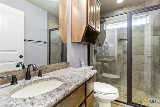 bathroom with vanity, an enclosed shower, and toilet