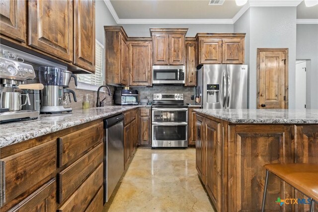 kitchen with sink, crown molding, decorative backsplash, light stone countertops, and stainless steel appliances