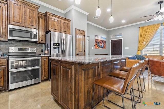 kitchen featuring light stone countertops, a center island, a kitchen bar, decorative backsplash, and appliances with stainless steel finishes