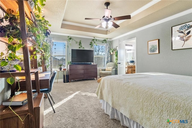 carpeted bedroom featuring a raised ceiling, connected bathroom, ceiling fan, and crown molding