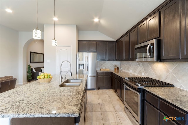 521 Kirkhill St, Hutto, TX 78634 - kitchen featuring appliances with stainless steel finishes, a sink, arched walkways, decorative backsplash, and vaulted ceiling