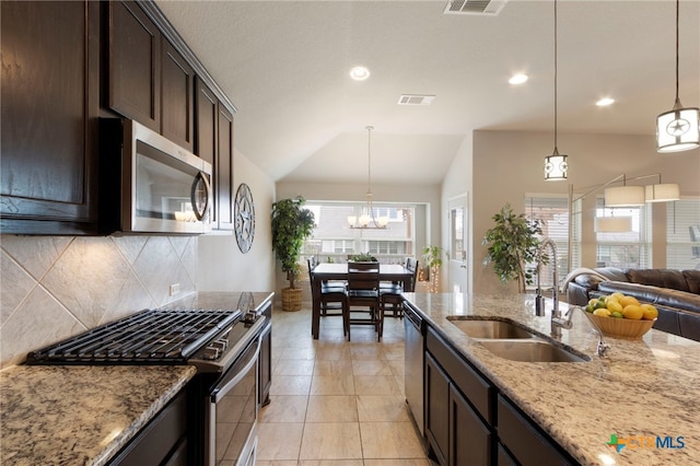 521 Kirkhill St, Hutto, TX 78634 - kitchen with appliances with stainless steel finishes, a sink, lofted ceiling, dark brown cabinetry, and tasteful backsplash