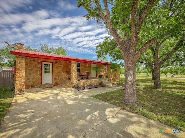 1003 Standifer St, Lampasas, TX 76550 - view of front facade with covered porch, stone siding, a chimney, and metal roof