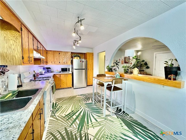 1003 Standifer St, Lampasas, TX 76550 - kitchen featuring white appliances, under cabinet range hood, brown cabinetry, light countertops, and a sink