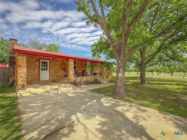 1003 Standifer St, Lampasas, TX 76550 - view of front of home featuring stone siding, covered porch, a front lawn, a chimney, and metal roof