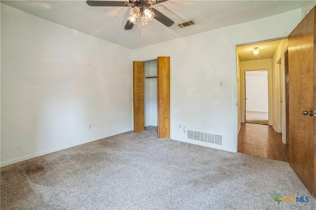 unfurnished bedroom featuring visible vents, carpet flooring, a textured ceiling, and baseboards