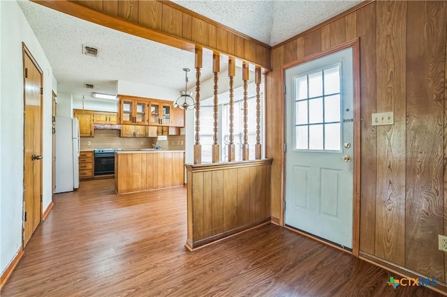 entryway with a textured ceiling, visible vents, wood walls, wood finished floors, and baseboards