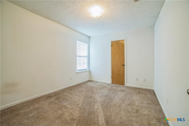 empty room featuring carpet floors, a textured ceiling, and baseboards