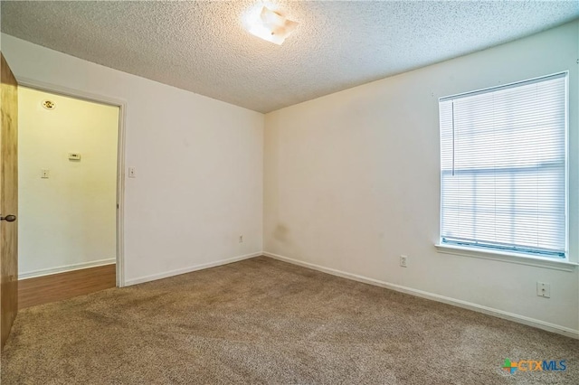 spare room with carpet floors, a textured ceiling, and baseboards