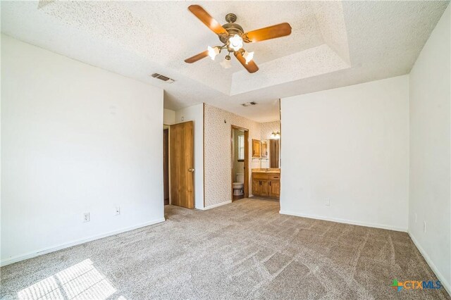 unfurnished bedroom featuring carpet floors, baseboards, a raised ceiling, and visible vents