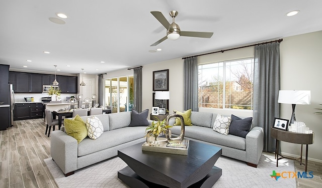 living room featuring a wealth of natural light, ceiling fan, and light wood-type flooring