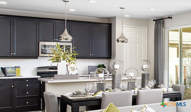 kitchen with tasteful backsplash, pendant lighting, appliances with stainless steel finishes, and a breakfast bar