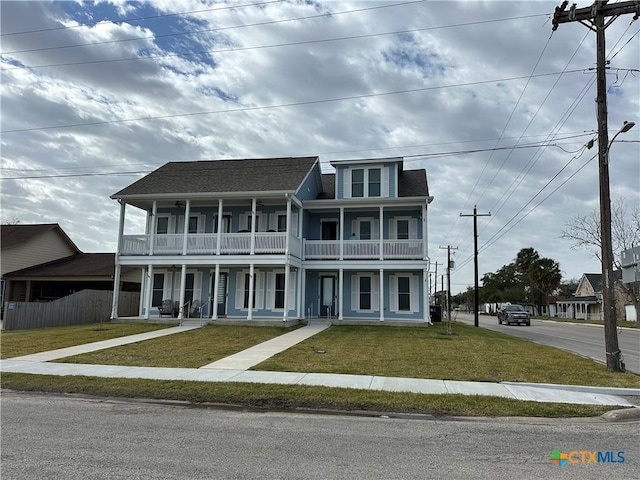 view of front of property with a balcony, roof with shingles, fence, a porch, and a front yard