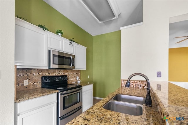 908 Pennsylvania Ave, Victoria, TX 77904 - kitchen with stainless steel appliances, decorative backsplash, white cabinetry, light stone countertops, and a peninsula