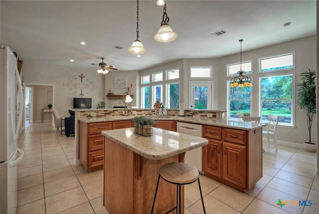 3701 Del Robles Dr, Austin, TX 78727 - kitchen with brown cabinets, plenty of natural light, freestanding refrigerator, a large island, and stainless steel dishwasher