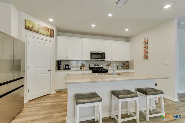 104 Hannah Trl, Georgetown, TX 78628 - kitchen featuring stainless steel appliances, a sink, light wood-type flooring, a breakfast bar, and recessed lighting