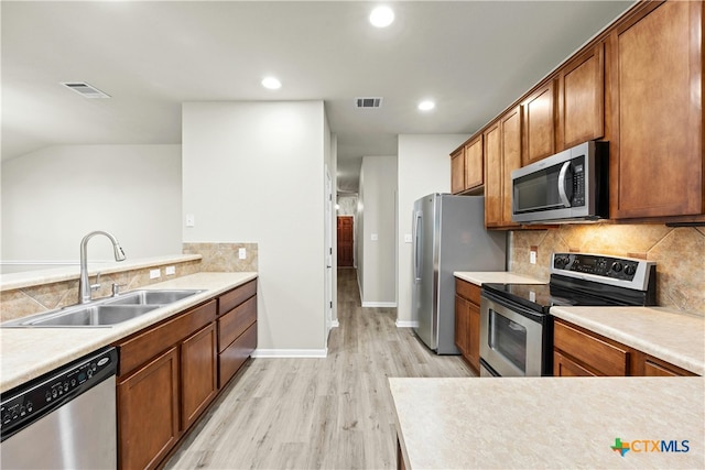 kitchen with sink, appliances with stainless steel finishes, tasteful backsplash, lofted ceiling, and light wood-type flooring