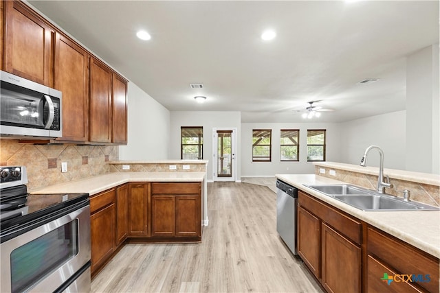 kitchen featuring sink, appliances with stainless steel finishes, ceiling fan, backsplash, and light hardwood / wood-style flooring